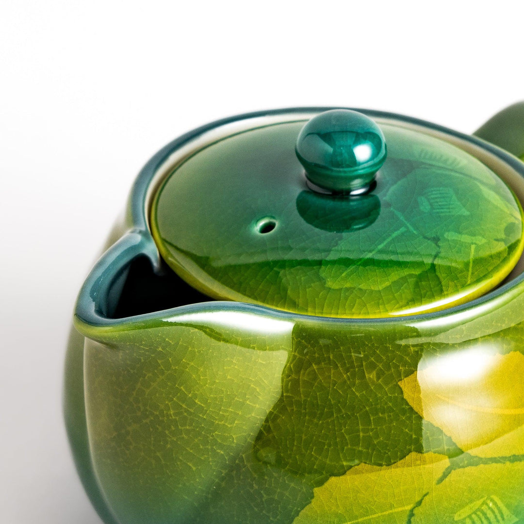 Glossy green ceramic teapot with a subtle leaf pattern, gradient design, and secure lid, perfect for brewing and serving your favorite tea.