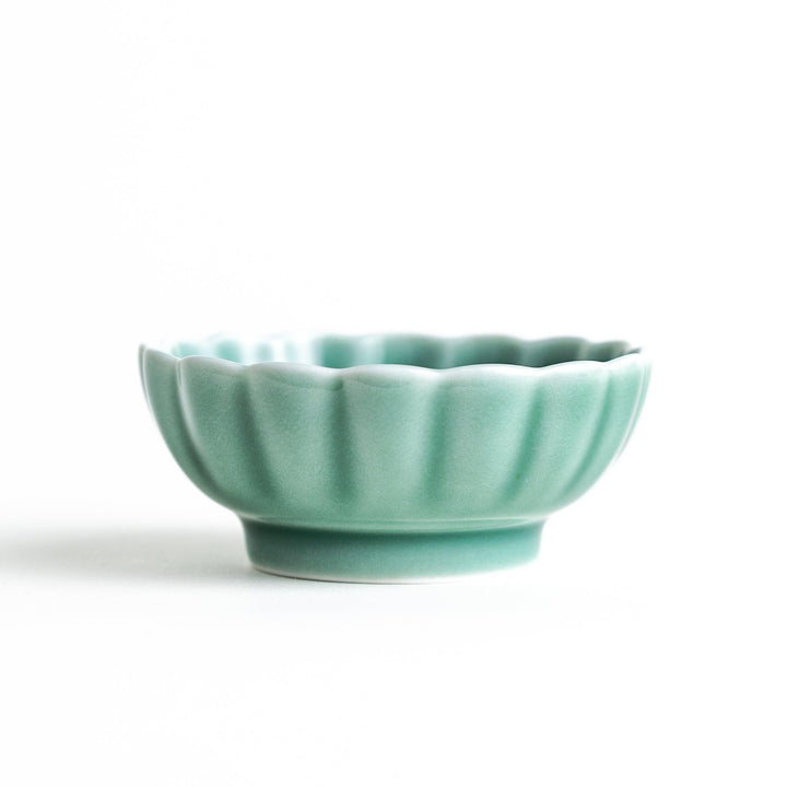 A small green cereal bowl with a scalloped edge and a blue and white wave pattern in the center.