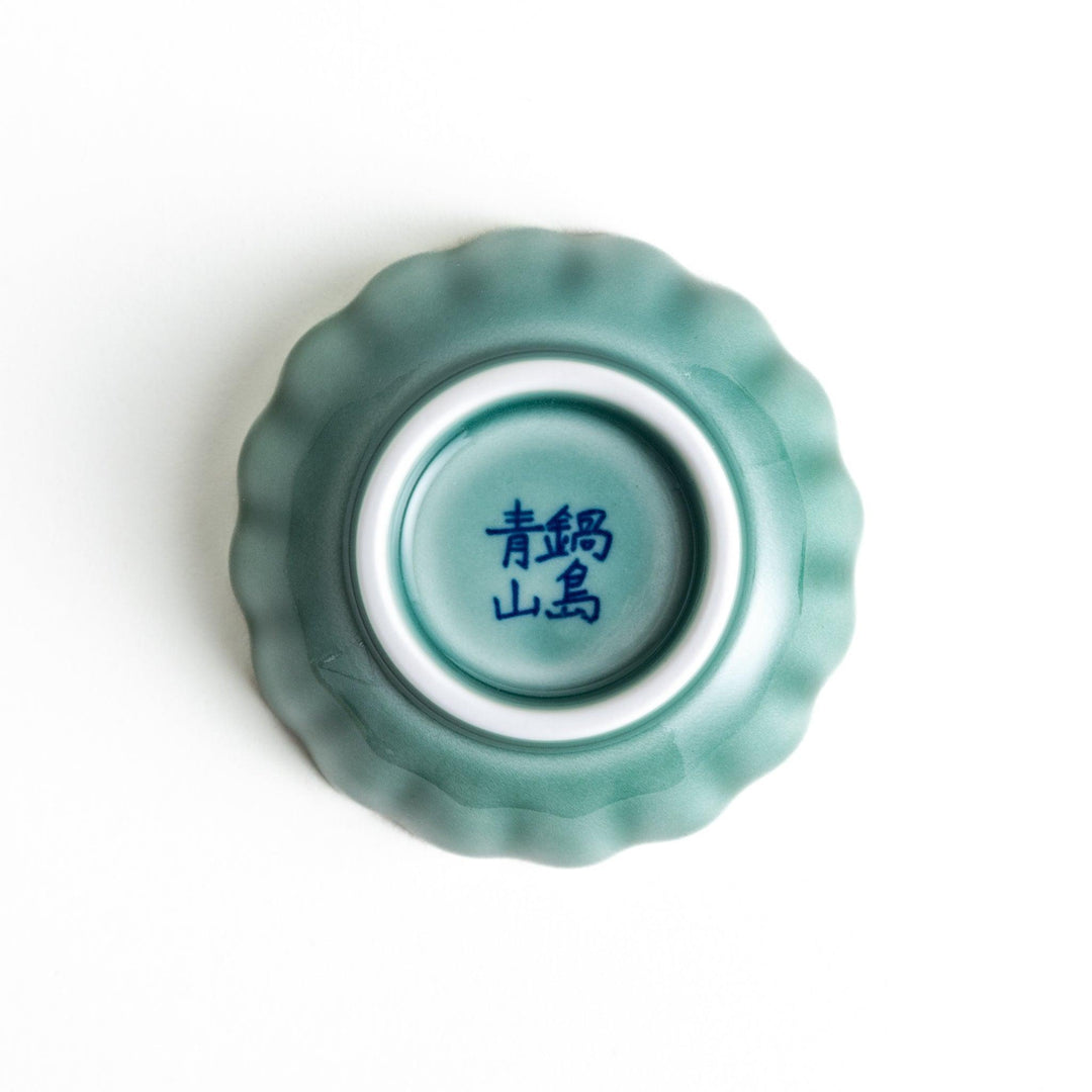 A small green cereal bowl with a scalloped edge and a blue and white wave pattern in the center.