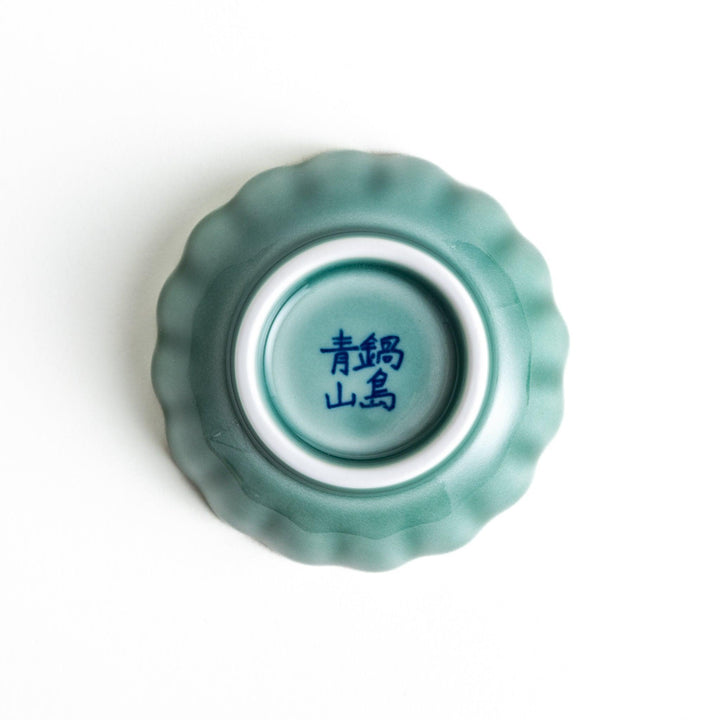 A small green cereal bowl with a scalloped edge and a blue and white wave pattern in the center.