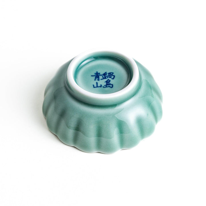 A small green cereal bowl with a scalloped edge and a blue and white wave pattern in the center.