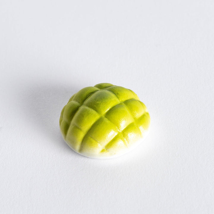 Chopstick rest shaped like a green melon pan, featuring intricate details to resemble the texture of the melon bun.