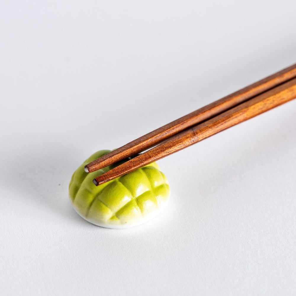Close-up of green melon pan chopstick rest with chopsticks placed on it, showcasing the detailed design of the melon bun.