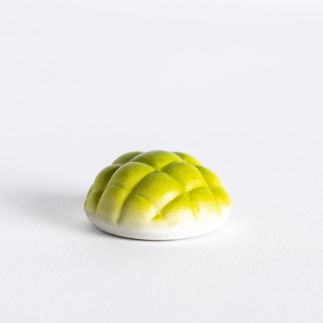Side view of green melon pan chopstick rest, highlighting its shape and the details that give it a realistic melon bun appearance.