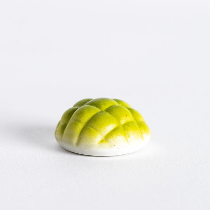 Side view of green melon pan chopstick rest, highlighting its shape and the details that give it a realistic melon bun appearance.