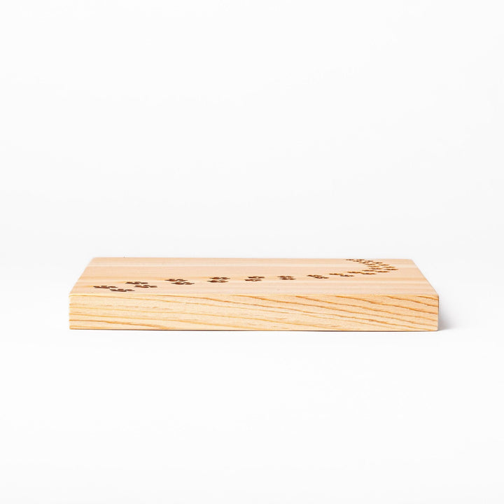 Square hinoki wood trivet featuring curved trail of laser-cut cat paw prints, protecting surfaces with charming feline design