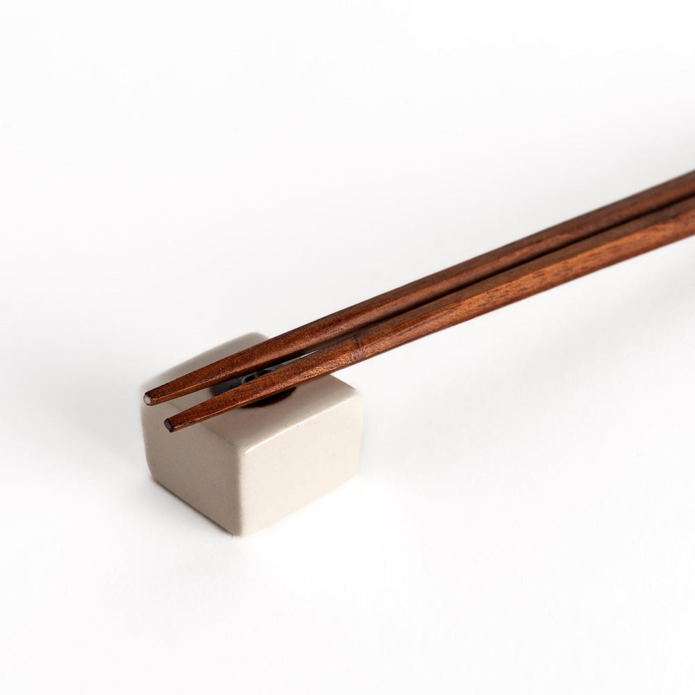 Wooden chopsticks resting on a ceramic hiyayakko tofu-inspired chopstick rest, highlighting its minimalist cube design and cultural charm.