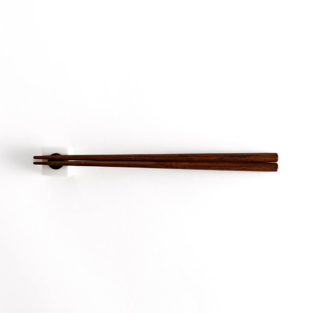Wooden chopsticks resting on a ceramic hiyayakko tofu-inspired chopstick rest, highlighting its minimalist cube design and cultural charm.