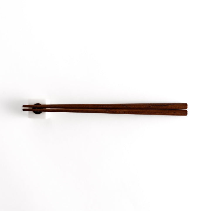 Wooden chopsticks resting on a ceramic hiyayakko tofu-inspired chopstick rest, highlighting its minimalist cube design and cultural charm.