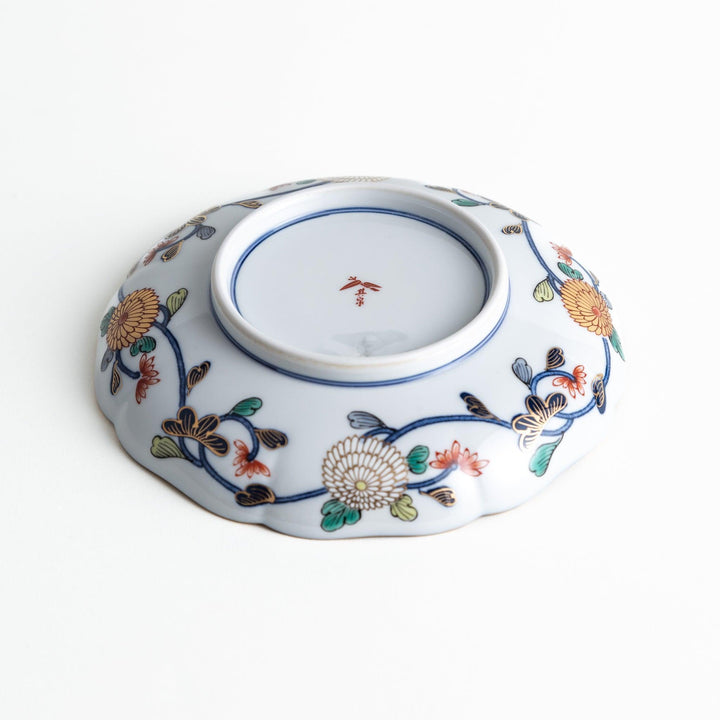 A deep round salad plate with a dark blue background, featuring a central floral design and intricate gold and red patterns with small scenes of Japanese landscapes.