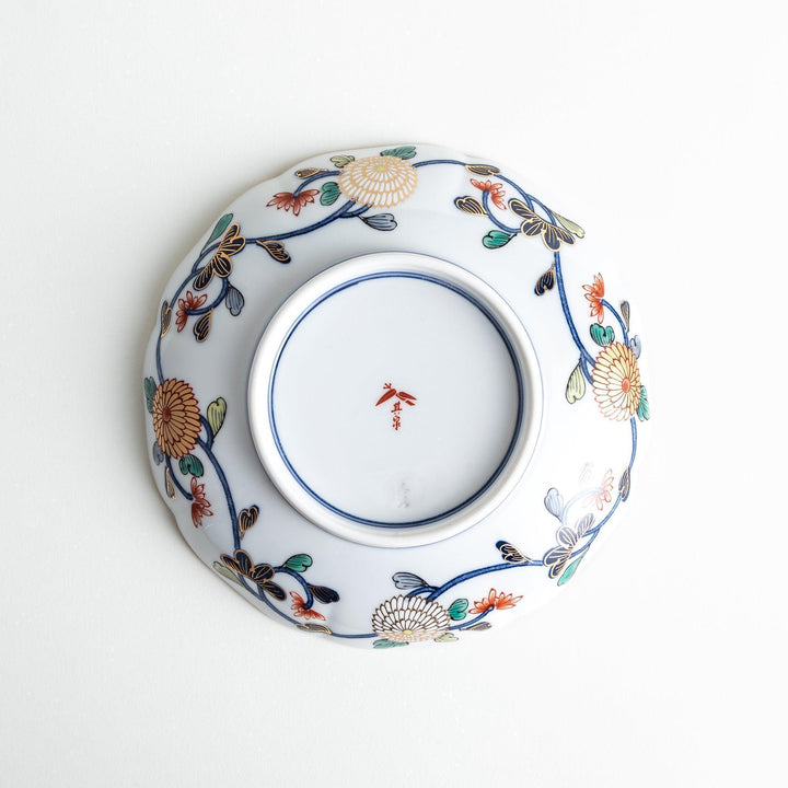A deep round salad plate with a dark blue background, featuring a central floral design and intricate gold and red patterns with small scenes of Japanese landscapes.