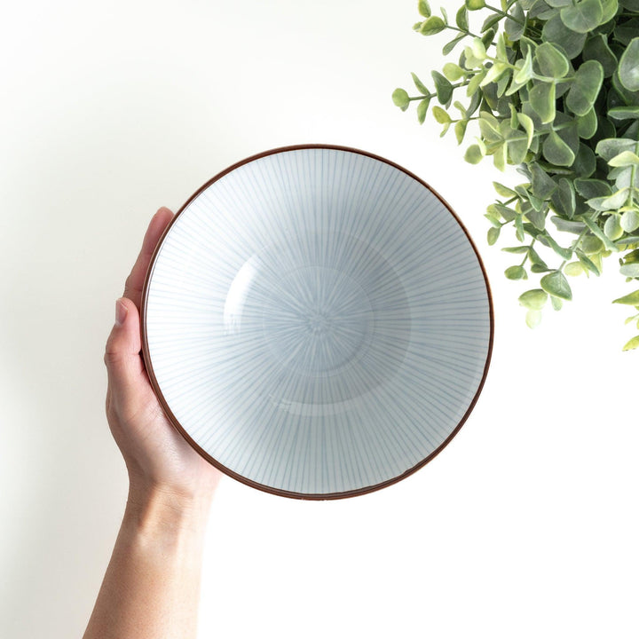 A white bowl with fine, vertical brown stripes and a brown rim, offering a sleek and modern design.