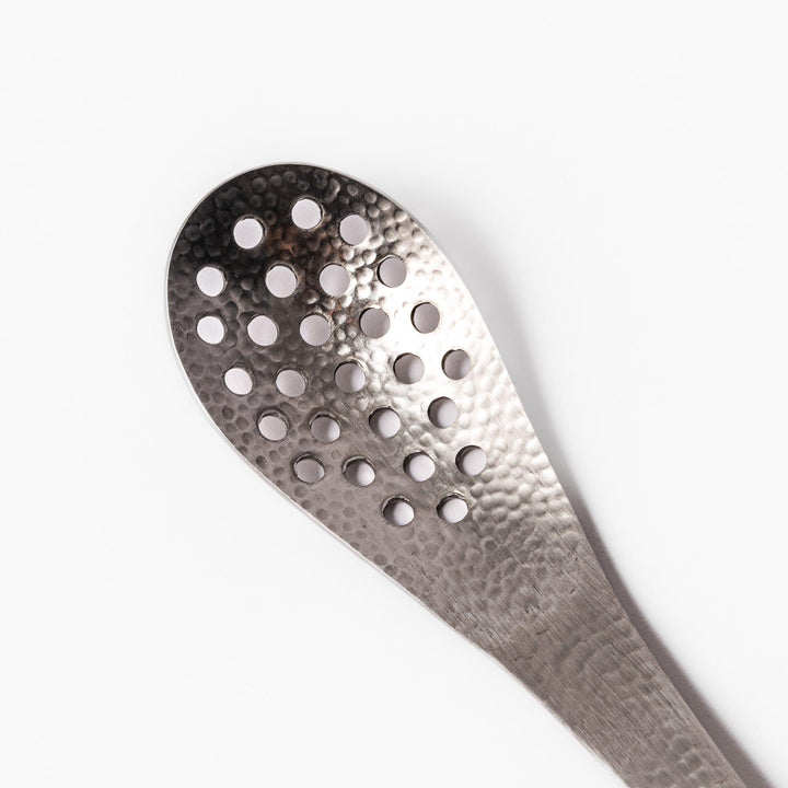 Handcrafted Japanese hammered straining spoon with perforated bowl, ideal for skimming or serving foods while draining excess liquid.