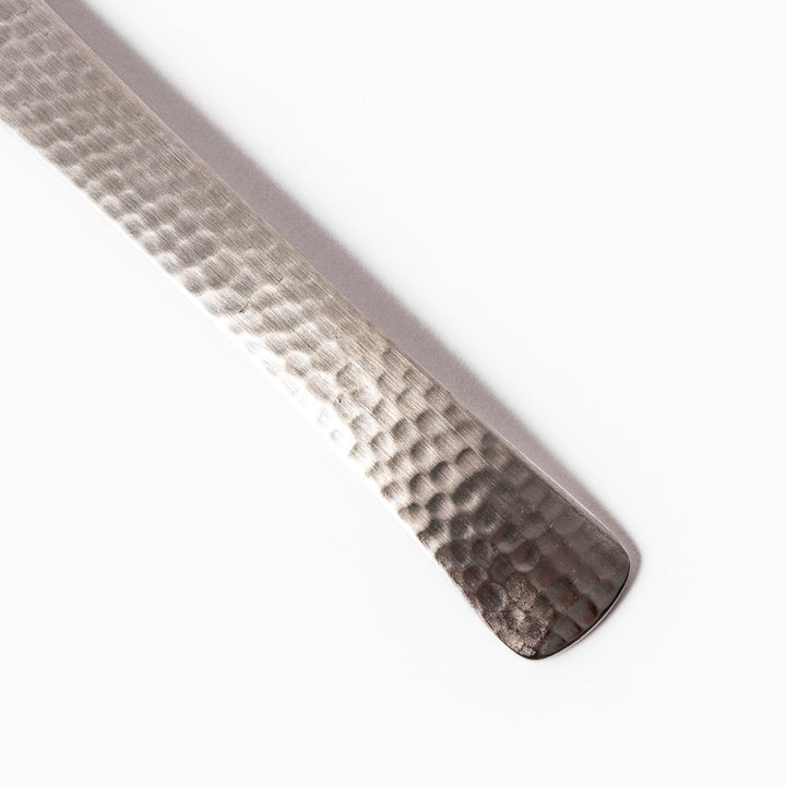 Handcrafted Japanese hammered straining spoon with perforated bowl, ideal for skimming or serving foods while draining excess liquid.