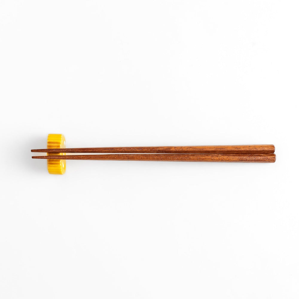 Chopstick rest shaped like a Japanese rolled omelette, featuring vibrant yellow details for a fun and authentic dining experience.