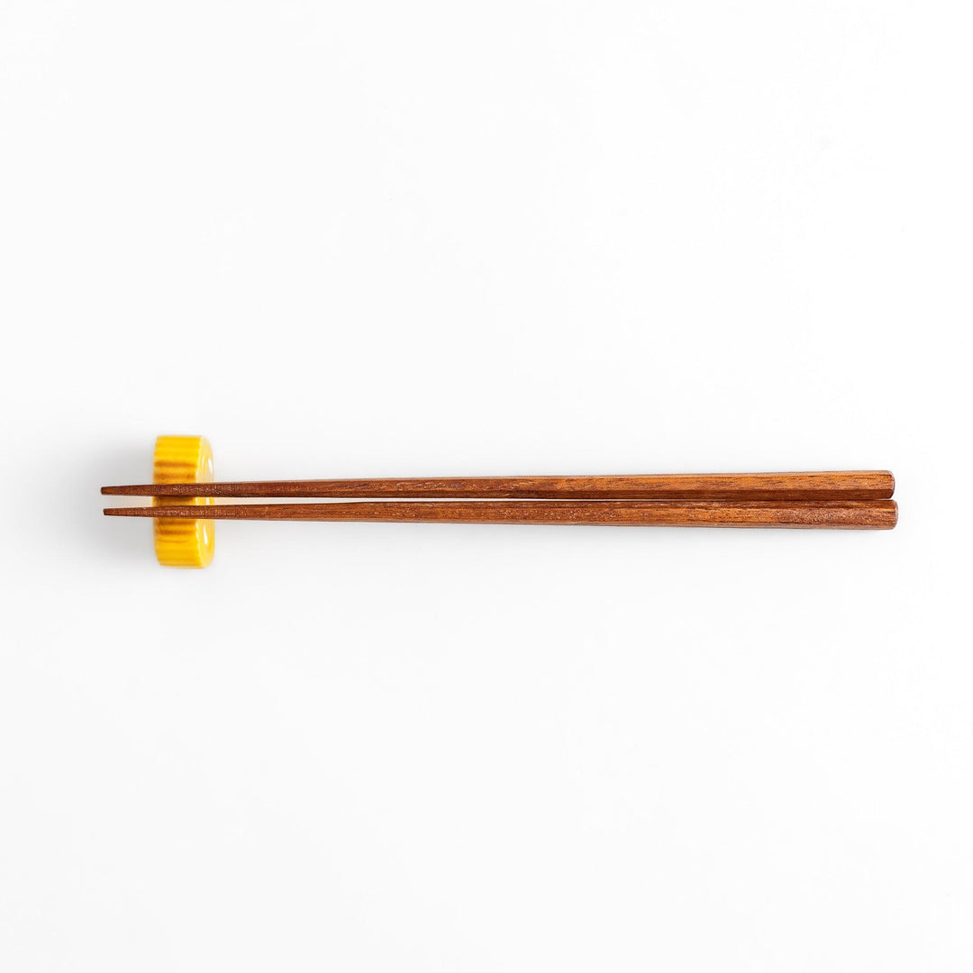 Chopstick rest shaped like a Japanese rolled omelette, featuring vibrant yellow details for a fun and authentic dining experience.