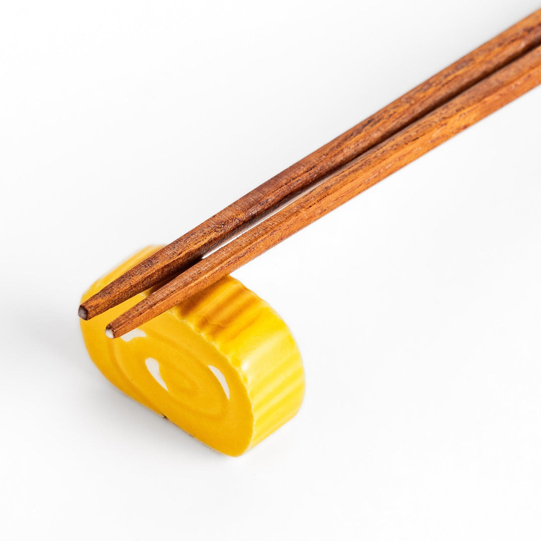 Chopstick rest shaped like a Japanese rolled omelette, featuring vibrant yellow details for a fun and authentic dining experience.