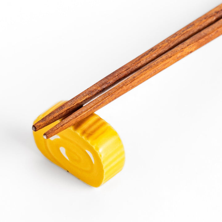 Chopstick rest shaped like a Japanese rolled omelette, featuring vibrant yellow details for a fun and authentic dining experience.