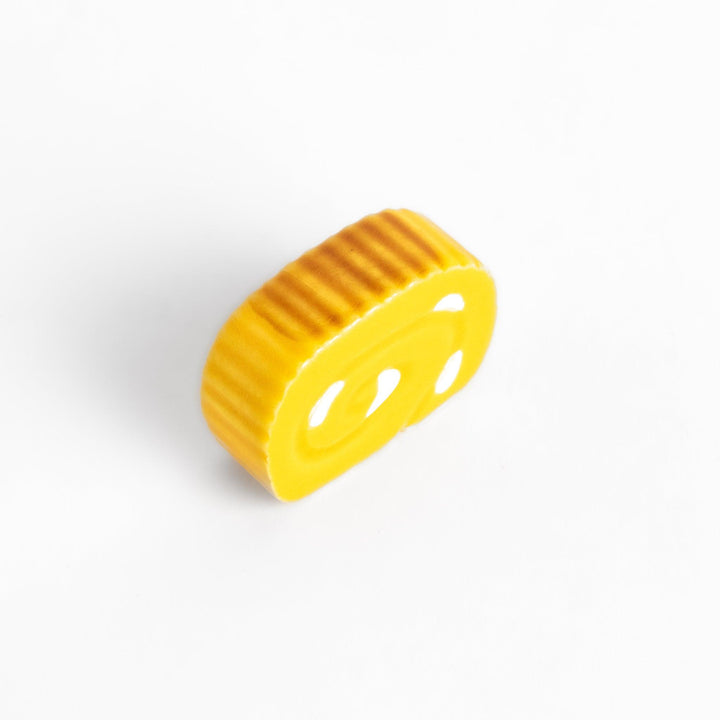 Chopstick rest shaped like a Japanese rolled omelette, featuring vibrant yellow details for a fun and authentic dining experience.