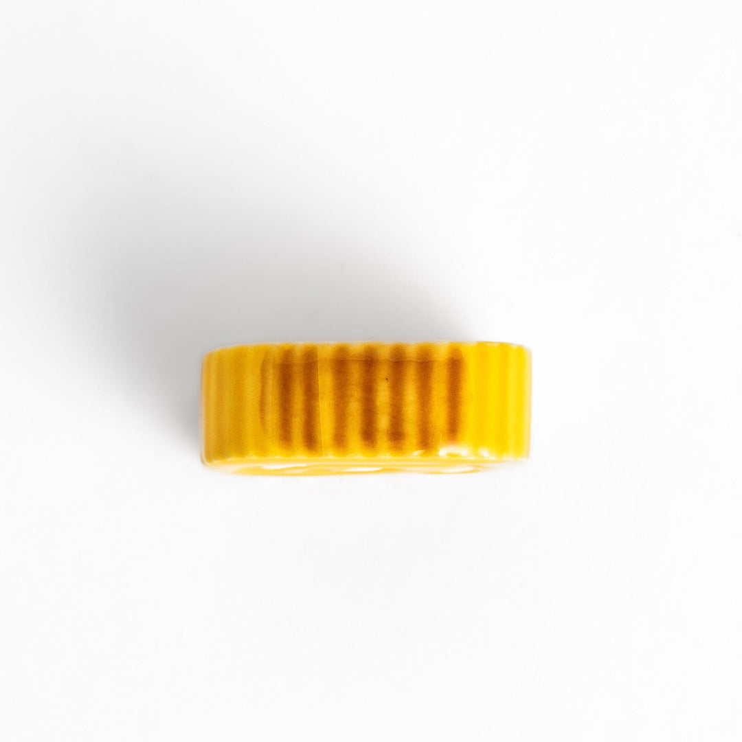 Chopstick rest shaped like a Japanese rolled omelette, featuring vibrant yellow details for a fun and authentic dining experience.