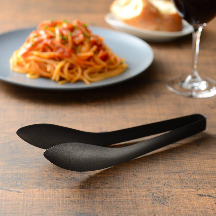 Sleek, matte black serving tongs with smooth curves, ideal for precise handling of small foods.
