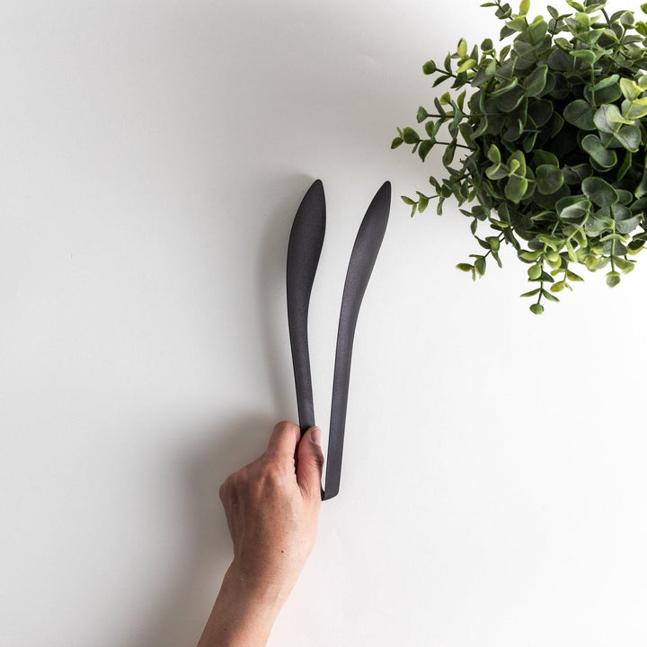 Sleek, matte black serving tongs with smooth curves, ideal for precise handling of small foods.