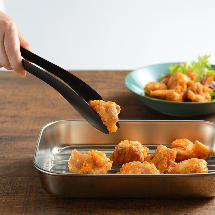 Sleek, matte black serving tongs with smooth curves, ideal for precise handling of small foods.
