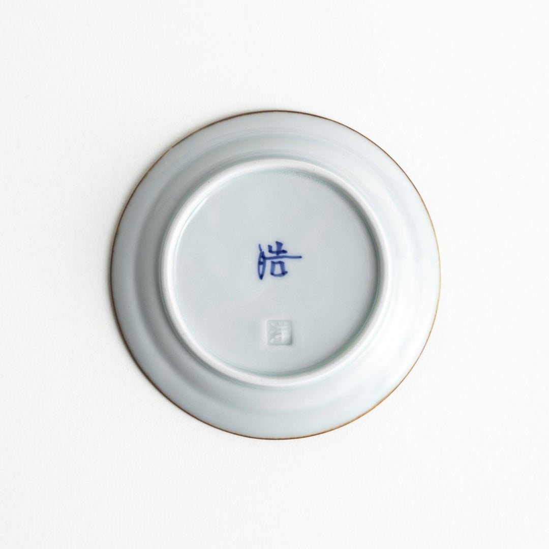 A small porcelain sauce dish with a scalloped edge, featuring a blue and white design of flowers and leaves and brown accent trim.