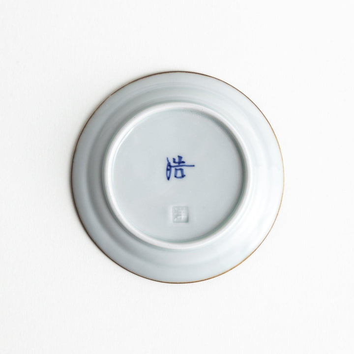 A small porcelain sauce dish with a scalloped edge, featuring a blue and white design of flowers and leaves and brown accent trim.