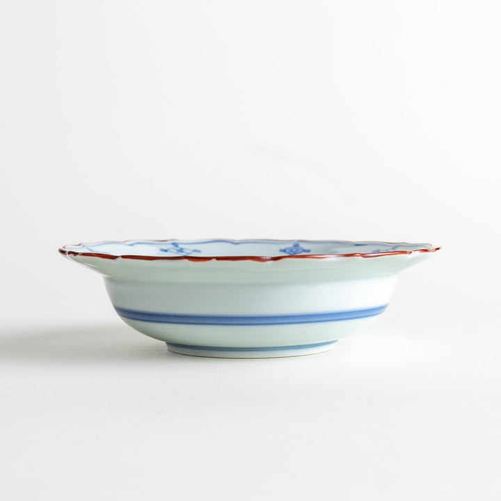 A ceramic bowl featuring a blue geometric motif and scalloped edges.