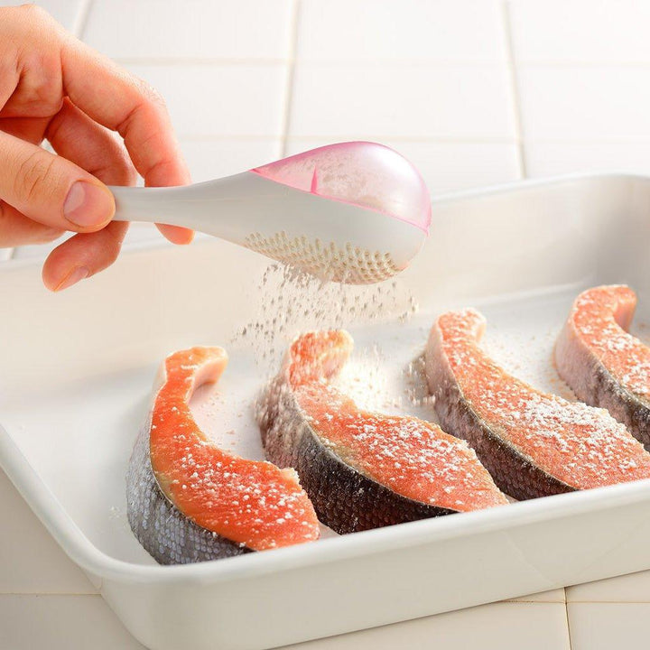 – A modern, white maraca-shaped spice sifter with a textured surface and a pink handle.