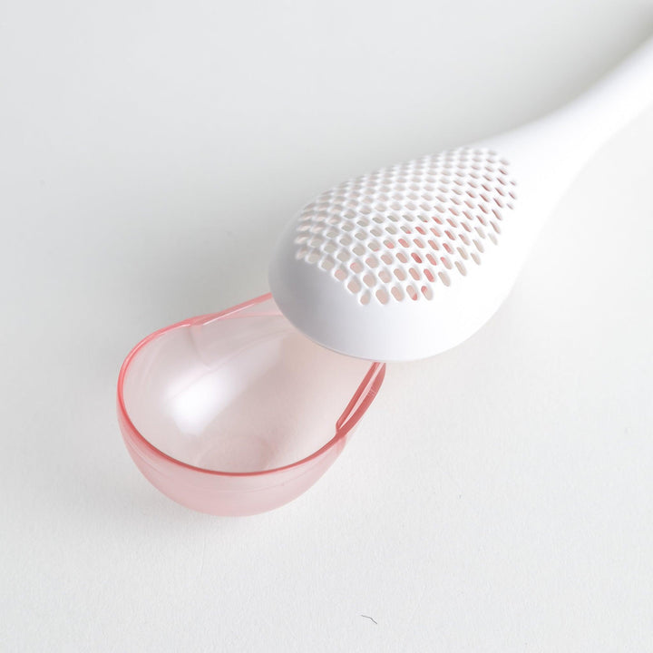 – A modern, white maraca-shaped spice sifter with a textured surface and a pink handle.