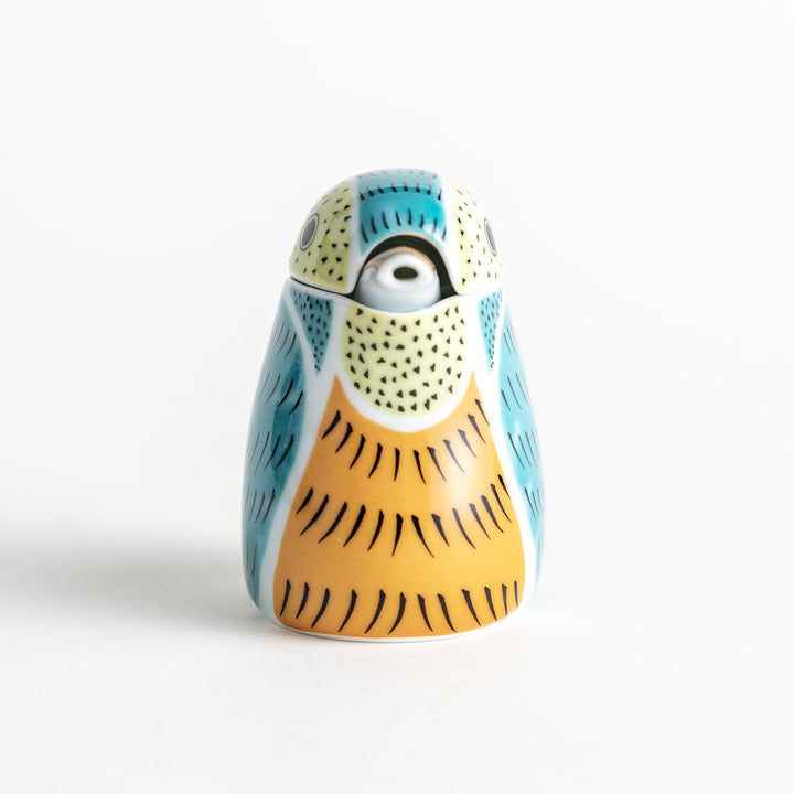 A bird-shaped ceramic soy sauce dispenser with vibrant patterns in turquoise, yellow, and green.