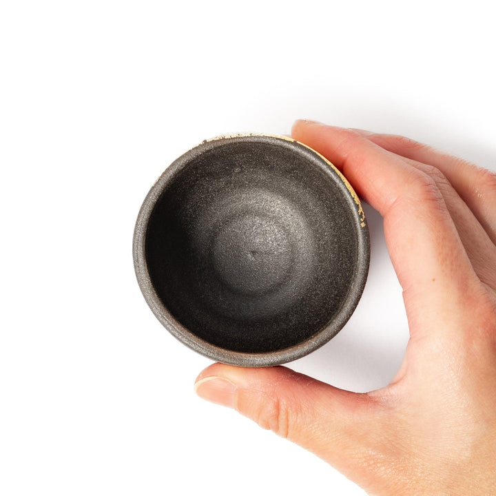Kintsugi-inspired black Kutani sake cup with bold gold crack design, blending traditional Japanese craftsmanship with contemporary elegance.