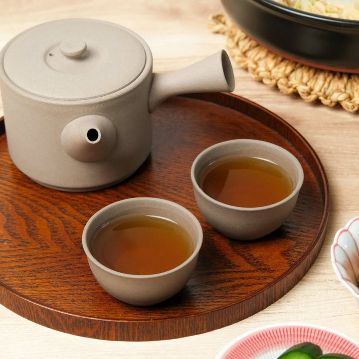 Large Cloud Whisper Gray Tea Set featuring a side-handle teapot and matching tea cups on a wooden tray, serving warm tea alongside a traditional Japanese meal.