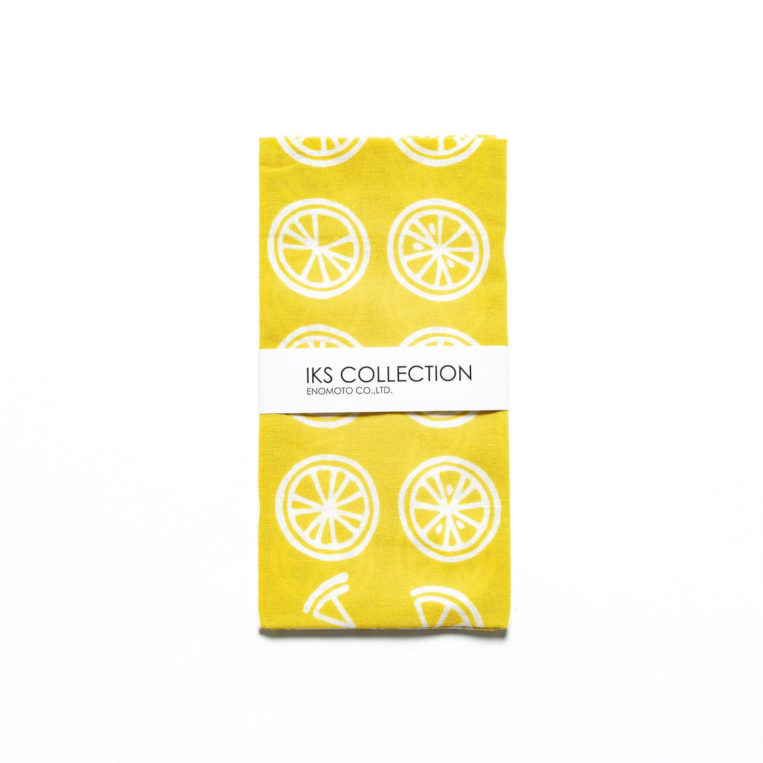 Yellow hand towel with white lemon slice motifs, folded with a branded sleeve.