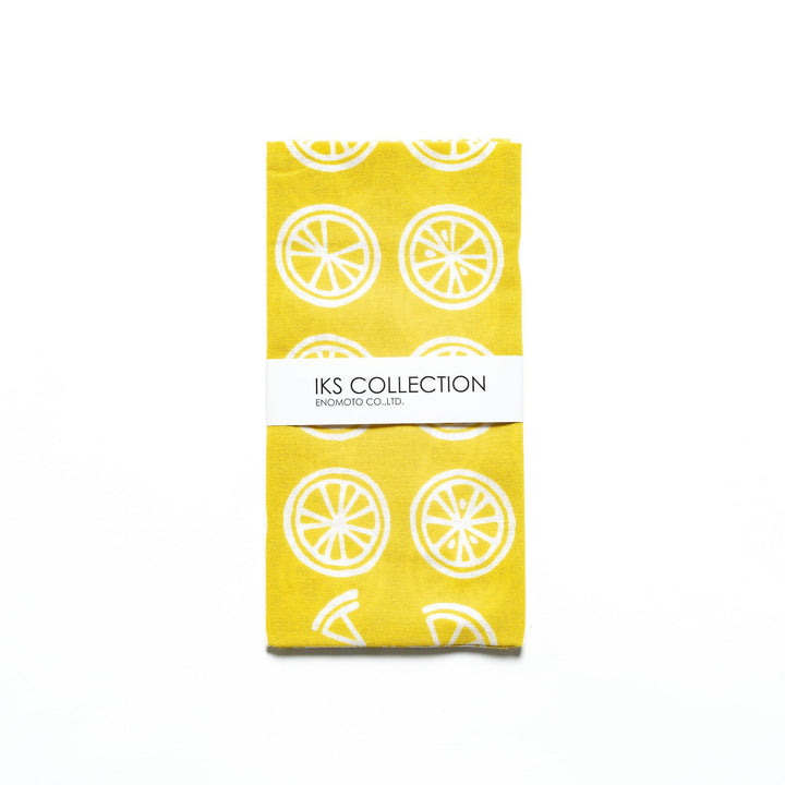 Yellow hand towel with white lemon slice motifs, folded with a branded sleeve.