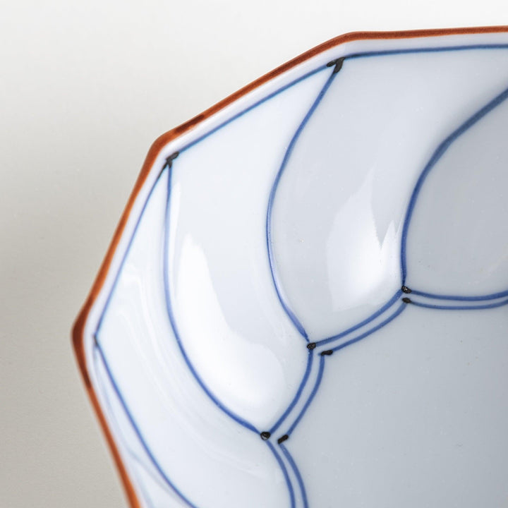 Deep white octagonal dessert bowl with a petal design, outlined in blue or red and finished with a brown rim.