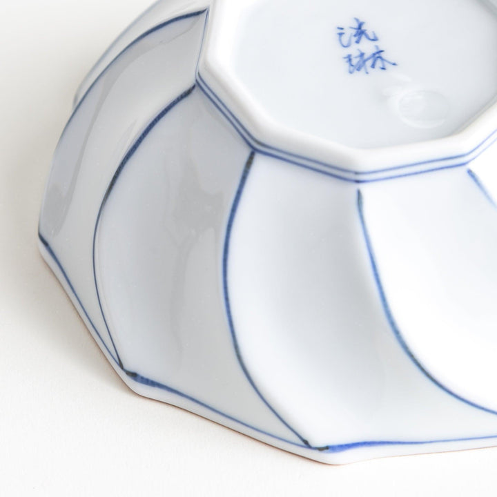 Deep white octagonal dessert bowl with a petal design, outlined in blue or red and finished with a brown rim.
