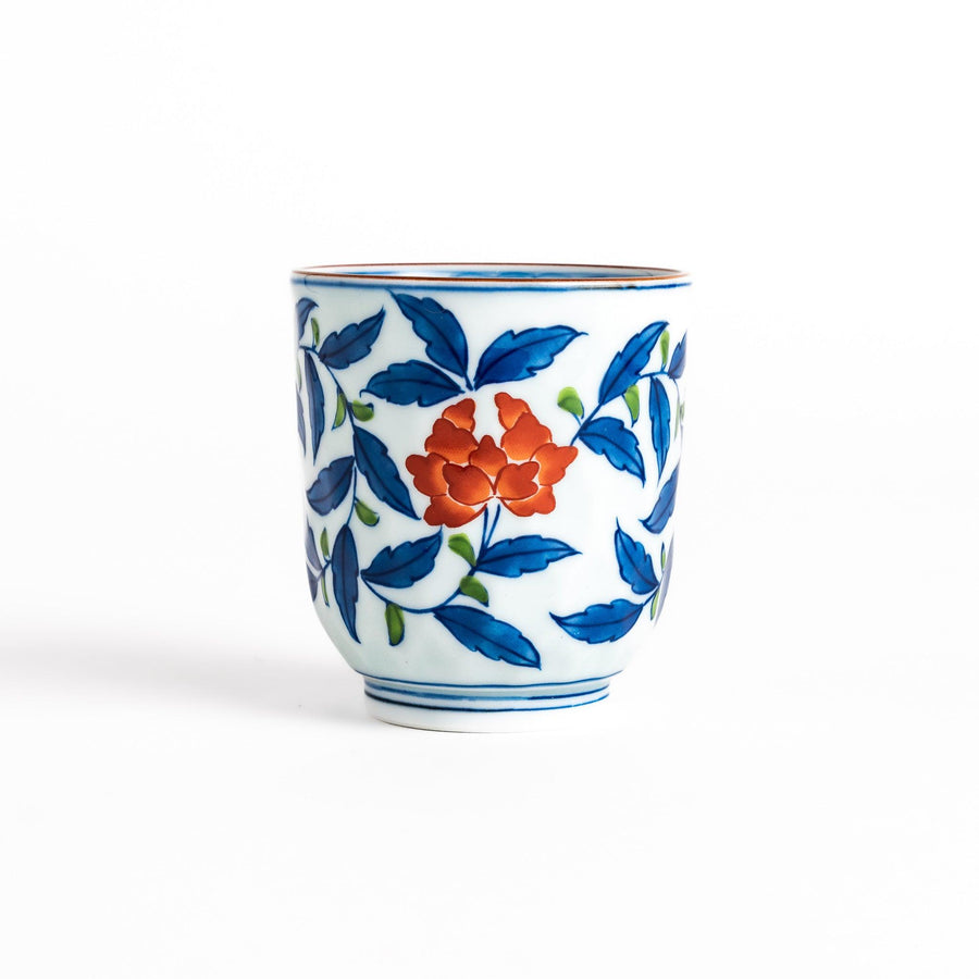 Elegant porcelain teacup with vibrant blue and orange floral design and green leaves, showcasing fine craftsmanship and vivid colors.