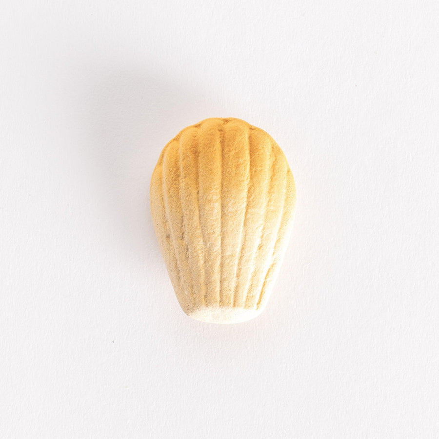 A ceramic chopstick rest shaped like a golden madeleine, showcasing its textured ridges on a white background.