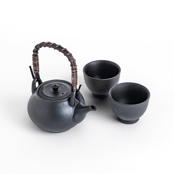 Matte black teapot with a woven handle, accompanied by two matching cups, creating a minimalist and elegant set for tea time, perfect for adding sophistication to your tea rituals.