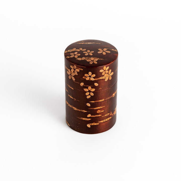 Traditional Japanese tea canister crafted from cherry bark with a delicate cherry blossom design, perfect for storing and preserving tea leaves.