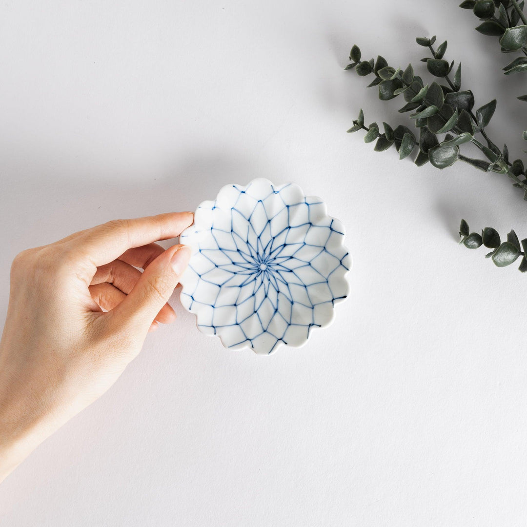 White sauce dish with a blue chrysanthemum mesh pattern and scalloped edges.