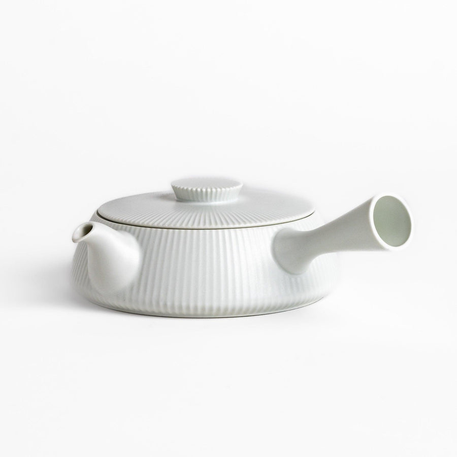 Minimalist ribbed white teapot with a sleek spout and a simple, elegant design, featuring a round lid with a textured top for a modern touch to your tea set.