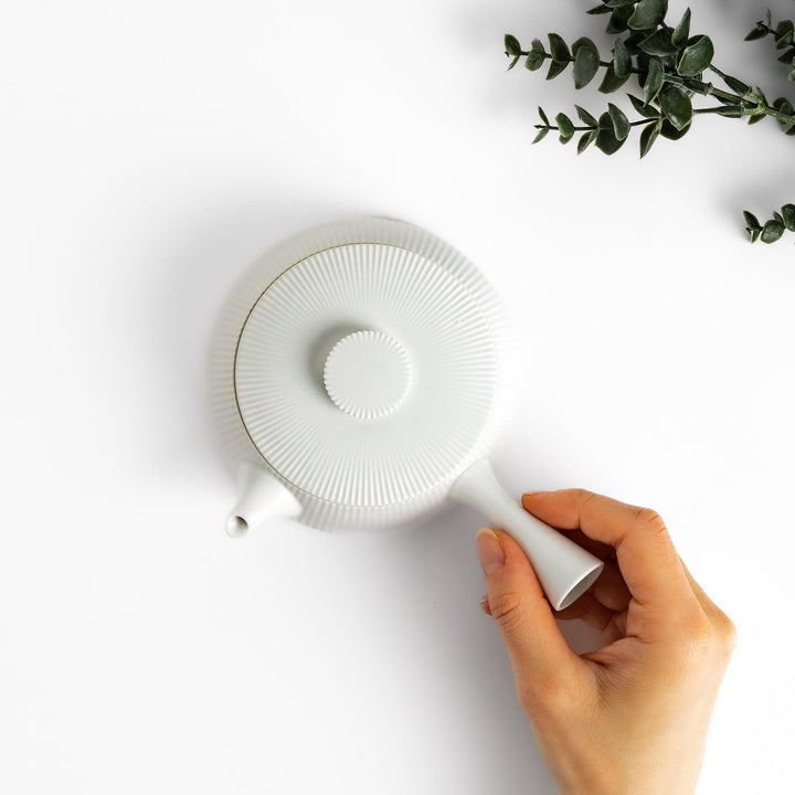 Minimalist ribbed white teapot with a sleek spout and a simple, elegant design, featuring a round lid with a textured top for a modern touch to your tea set.