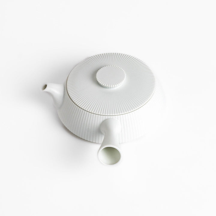 Minimalist ribbed white teapot with a sleek spout and a simple, elegant design, featuring a round lid with a textured top for a modern touch to your tea set.