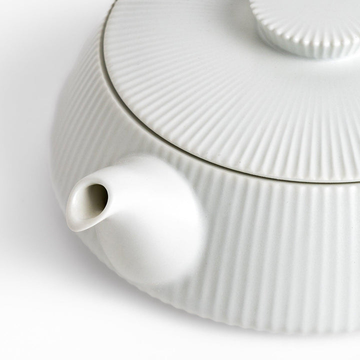 Minimalist ribbed white teapot with a sleek spout and a simple, elegant design, featuring a round lid with a textured top for a modern touch to your tea set.