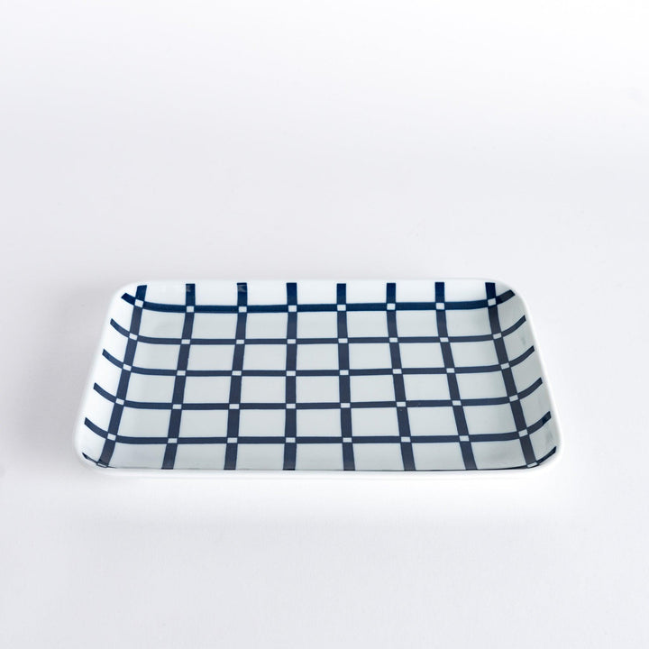 A slightly angled view of the Modern Indigo Lattice Dinner Plate, showing the navy blue lattice design in a grid pattern against a white surface.