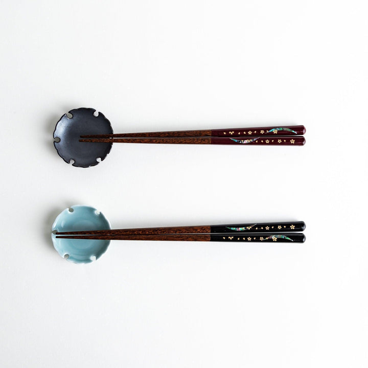 Two pairs of chopsticks, one with red and one with black handles, featuring moon and sakura design.